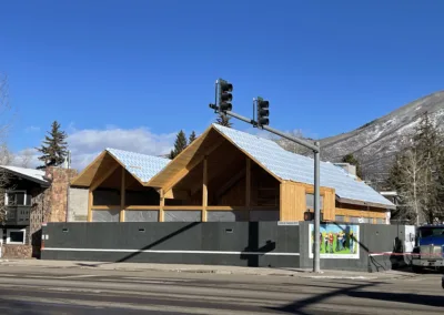 Newly constructed building with a snow-covered roof behind a traffic light.