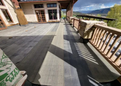 Construction materials on a partially completed deck with a mountain view in the background.