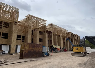 Construction site with partially built wooden frame structures and heavy machinery.