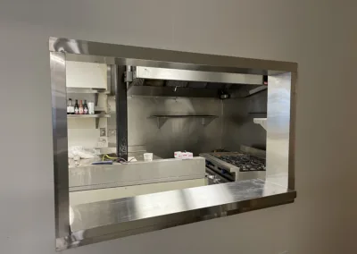 View of a commercial kitchen through a serving hatch.