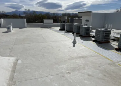 Rooftop with hvac units and mountainous backdrop under a cloudy sky.