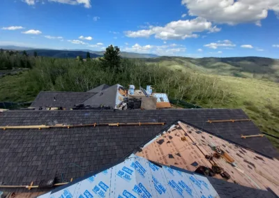 Rooftop under renovation with a scenic backdrop of green hills and a clear sky.