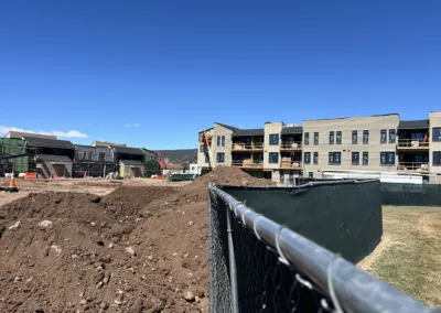 Construction site with partially completed buildings and earthworks on a clear day.