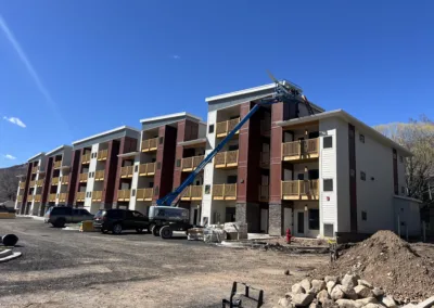 New apartment building under construction with workers and construction equipment on site.