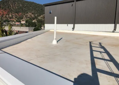 Flat roof with a single vent pipe and the shadow of a person on a ladder.